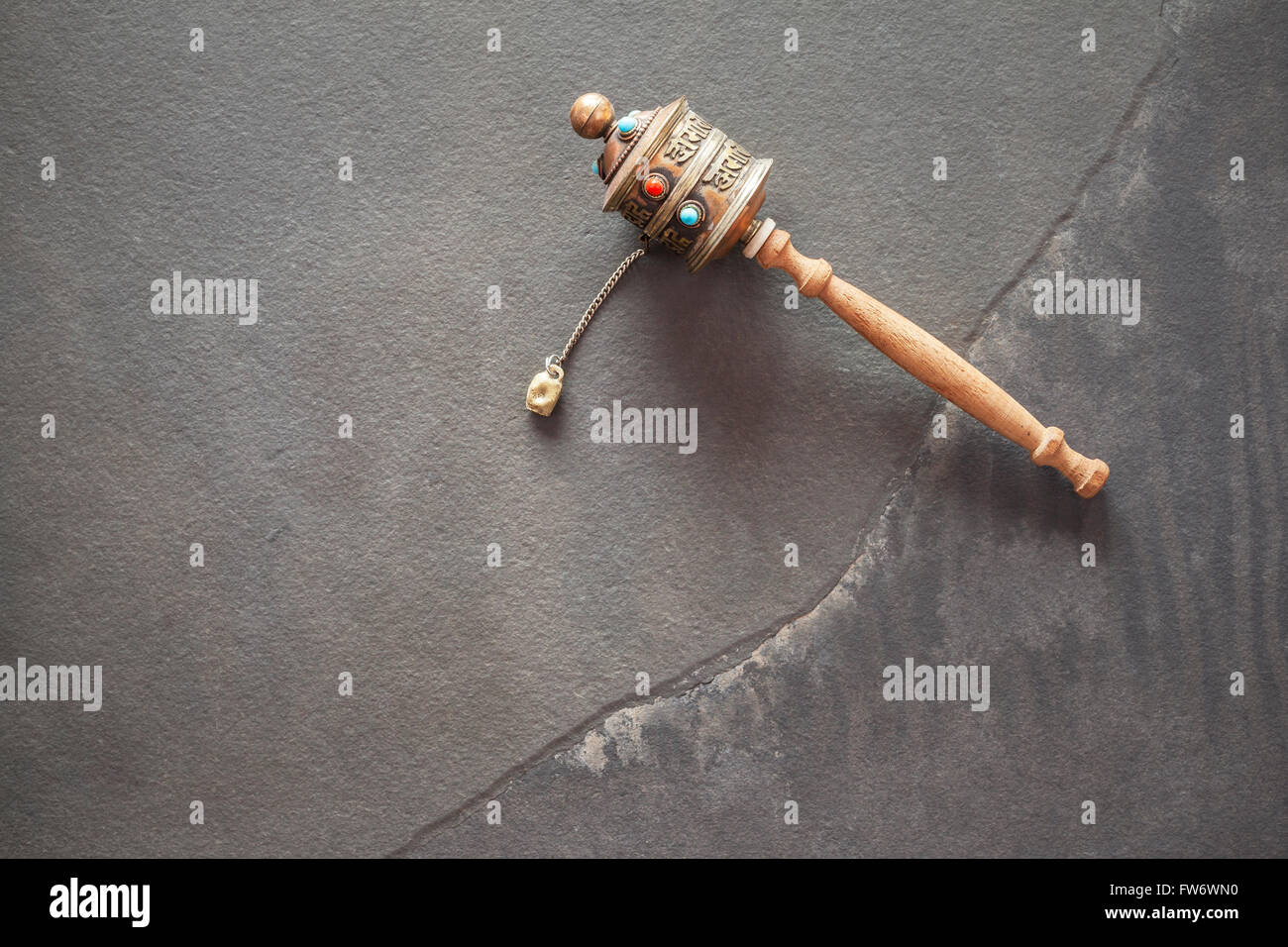 Old Tibetan prayer wheel on stone background, used to accumulate wisdom and good karma and to purify bad karma. Stock Photo