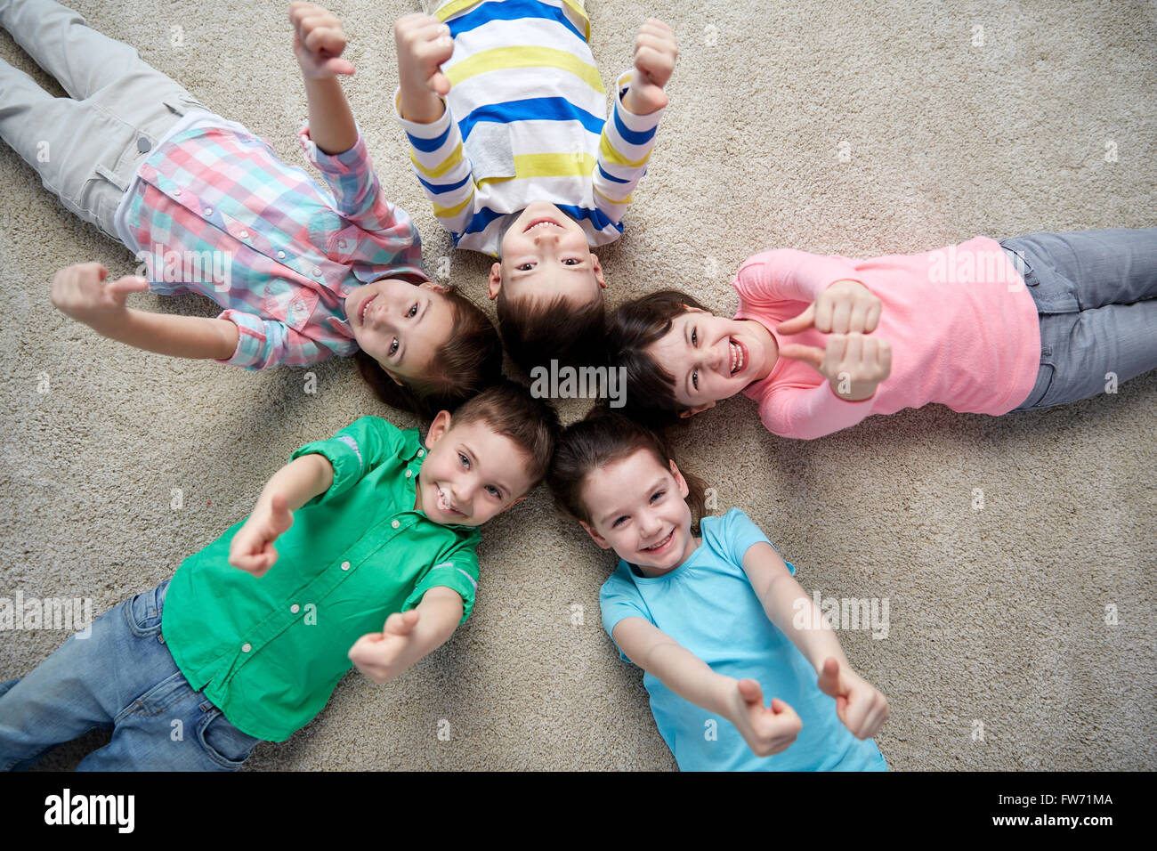 happy kids lying on floor and showing thumbs up Stock Photo - Alamy