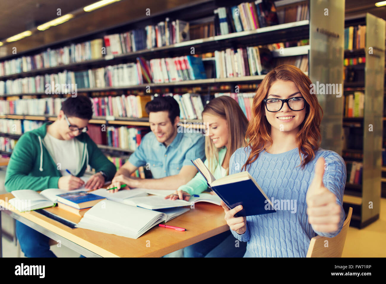 happy student girl showing thumbs up in library Stock Photo - Alamy