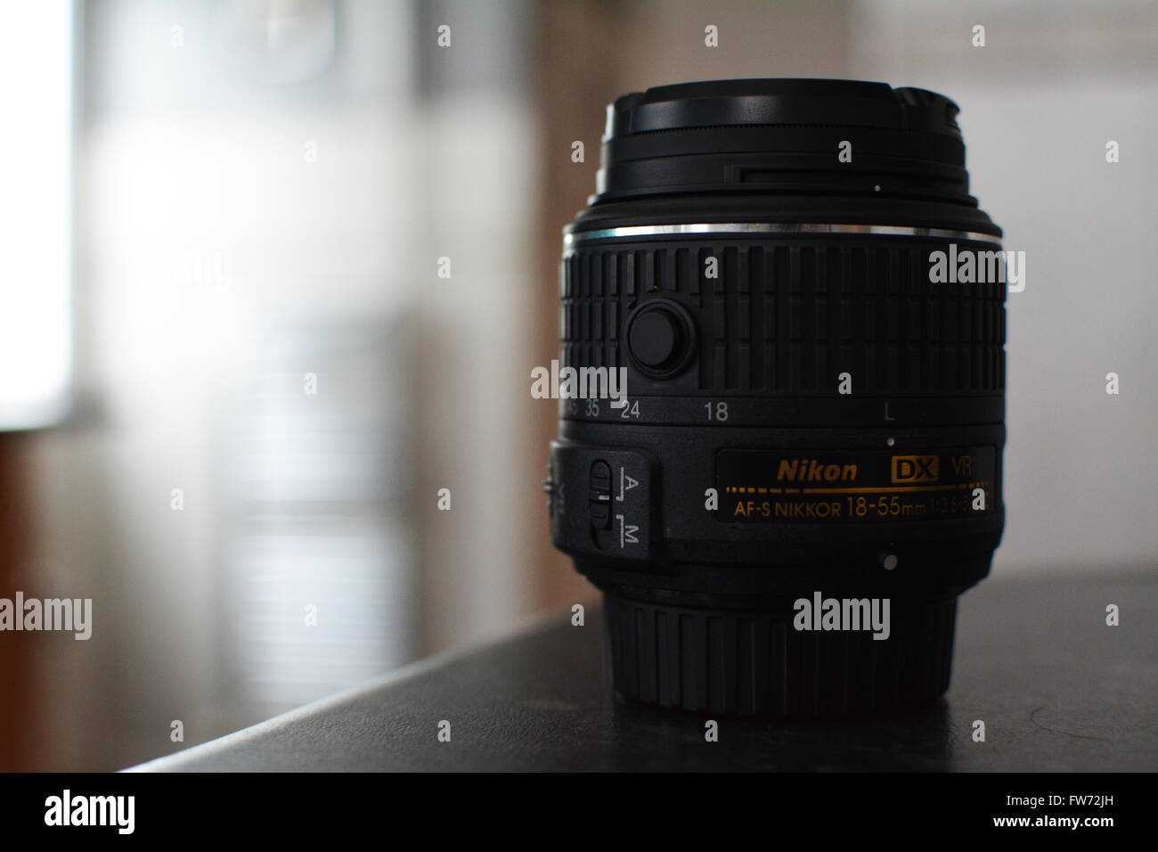 Nikon kit lens not mounted to a camera body. Bokeh background & light pouring through a window. The lens is a 18-55mm VR DX. Stock Photo
