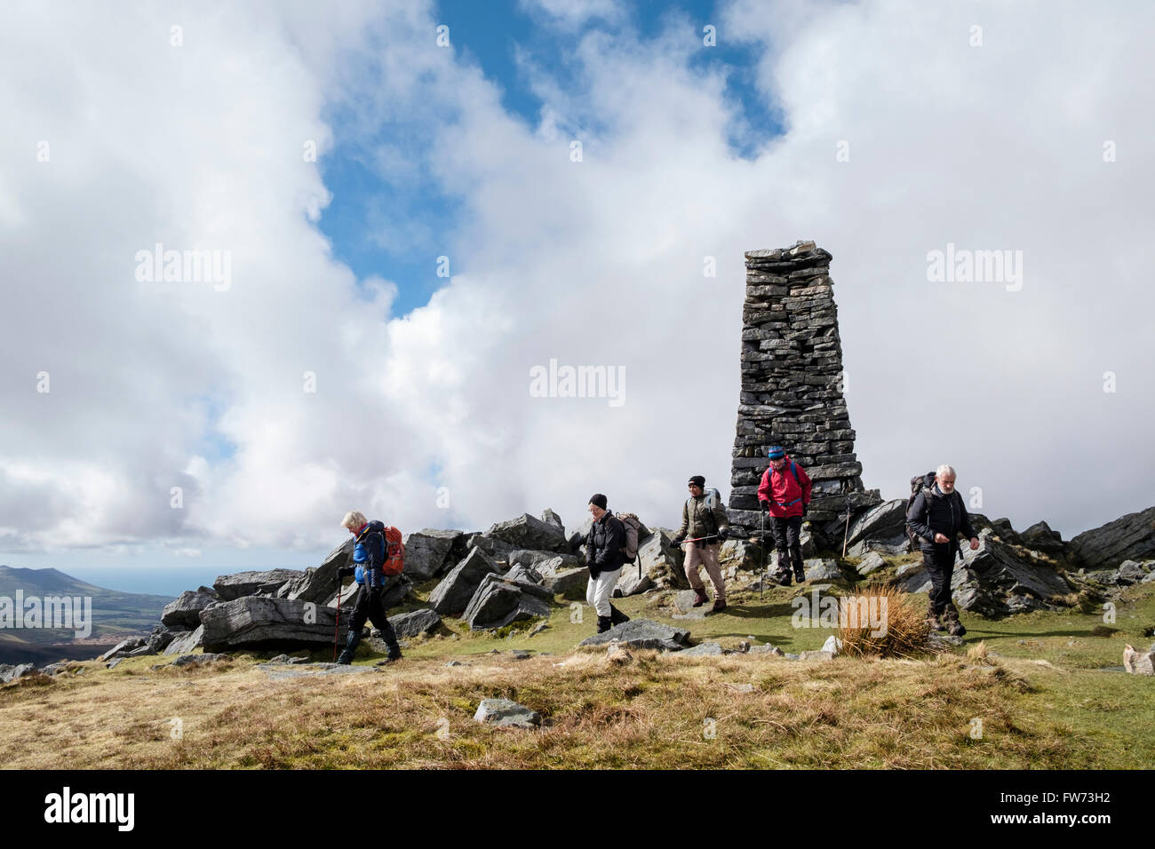 Hikers by Obelisk on Mynydd Tal-y-mignedd mountain on Crib Nantlle Ridge in mountains of Snowdonia National Park. Wales UK Britain Stock Photo