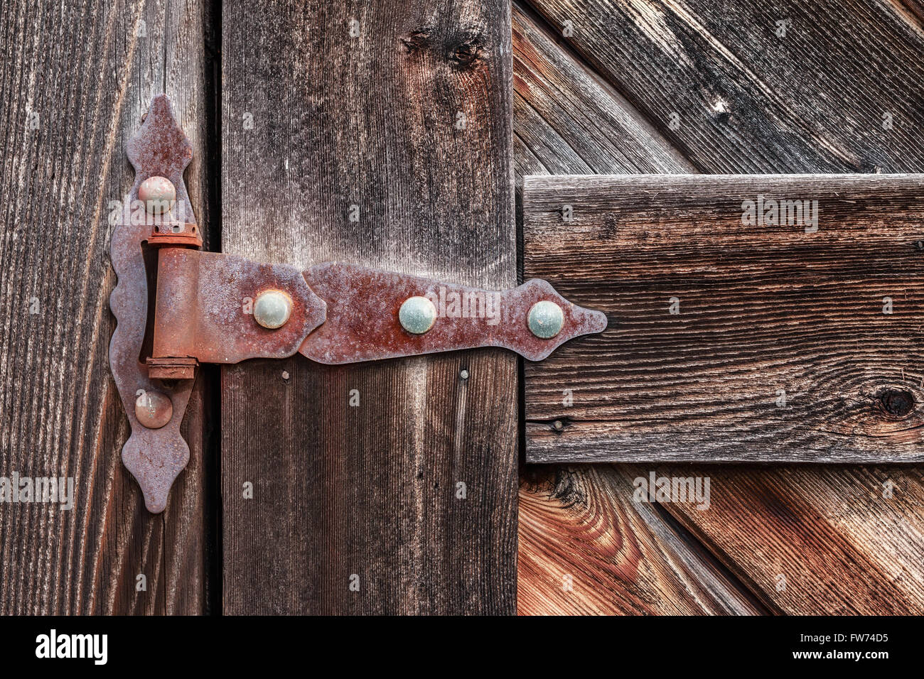 Old rusty hinge on wooden weathered door. Stock Photo