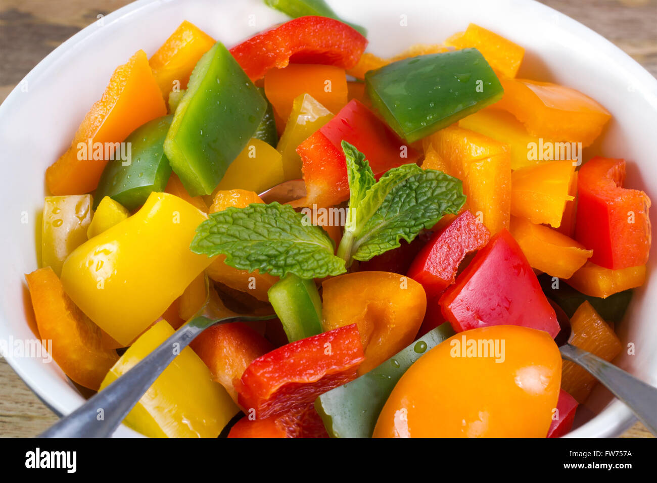 Close up on pepper salad decorated with mint in bowl on wooden table Stock Photo