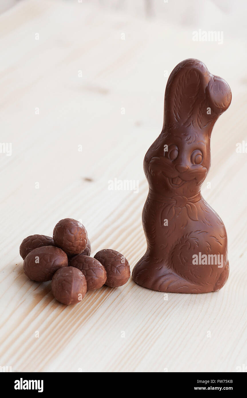Unwrapped chocholate Easter Bunny with eggs on a wooden table Stock Photo
