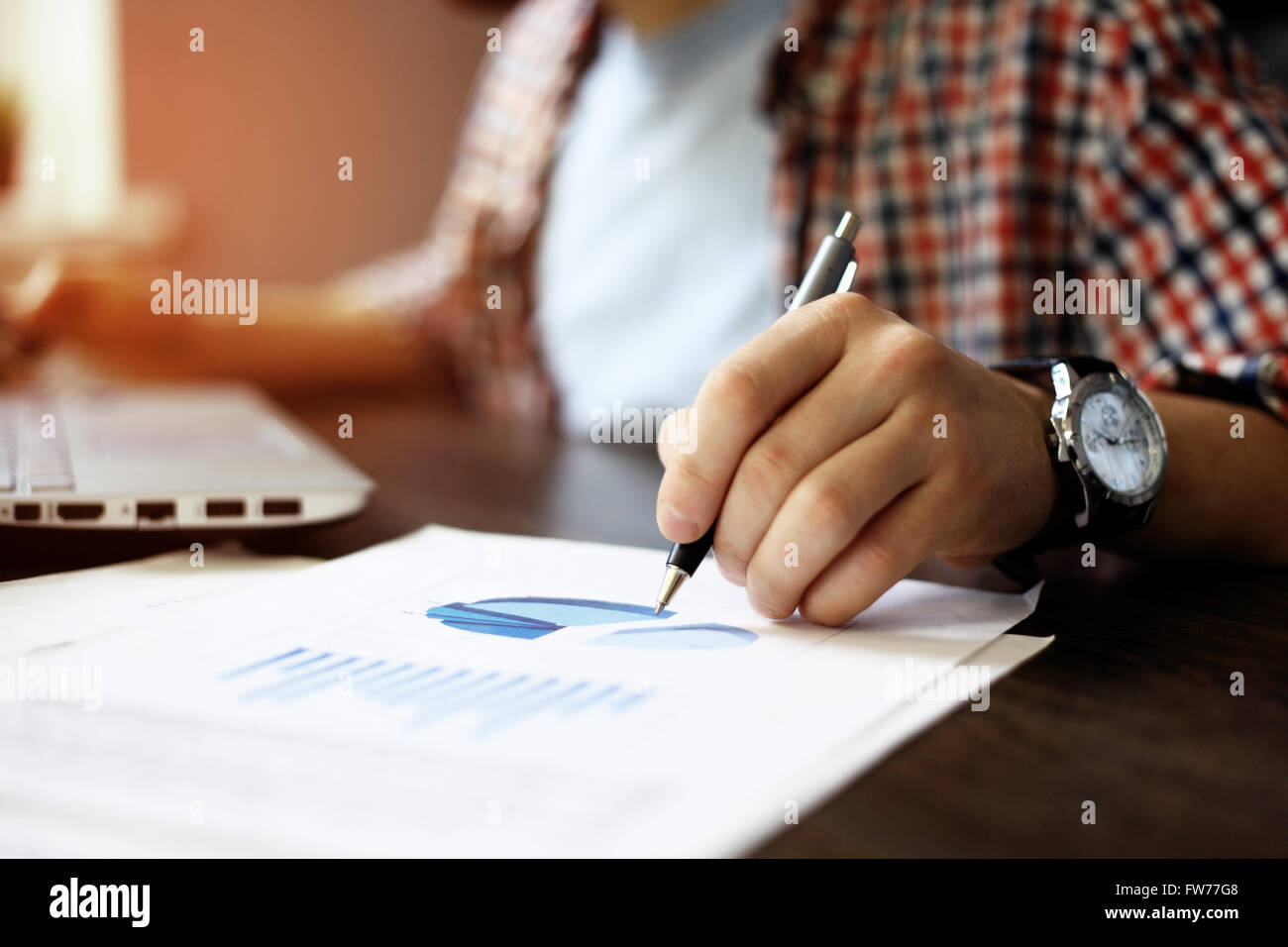 close up of business man hand working on laptop computer with business graph information diagram on wooden desk Stock Photo