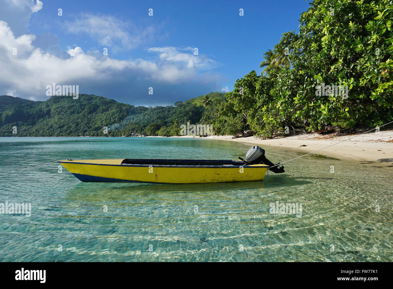 Small motor boat moored on sandy shore with tropical vegetation, Avea bay, Huahine Iti island, Pacific ocean, French Polynesia Stock Photo