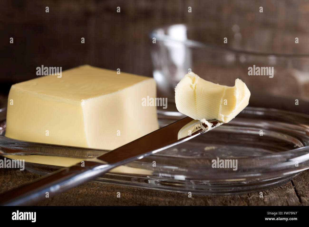 Knife with butter and butter dish in background Stock Photo