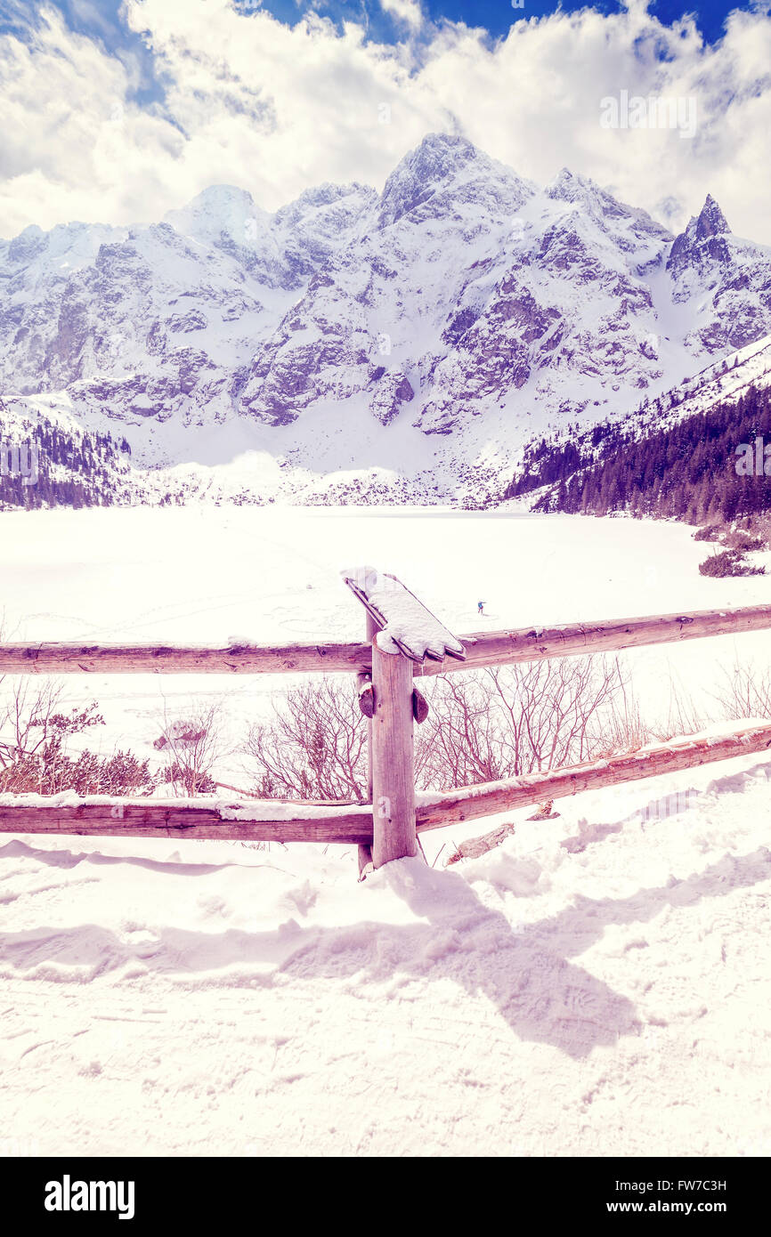 Vintage stylized wooden railing at frozen lake Morskie Oko in Polish Tatra Mountains, most popular mountain lake in Poland. Stock Photo