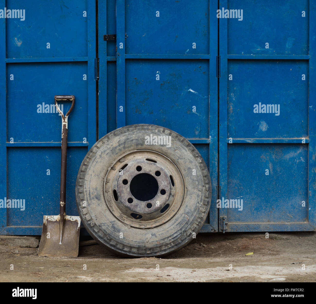 Truck wheel and a shovel on background of garage doors Stock Photo