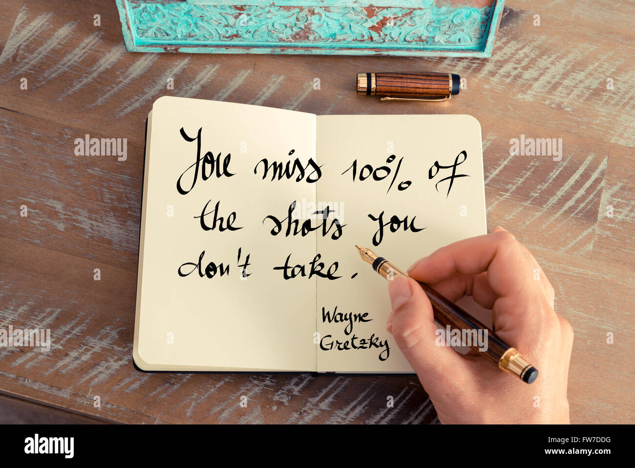 Retro effect and toned image of a woman hand writing on a notebook. Handwritten quote You miss 100% of the shots you don't take. - Wayne Gretzky as inspirational concept image Stock Photo