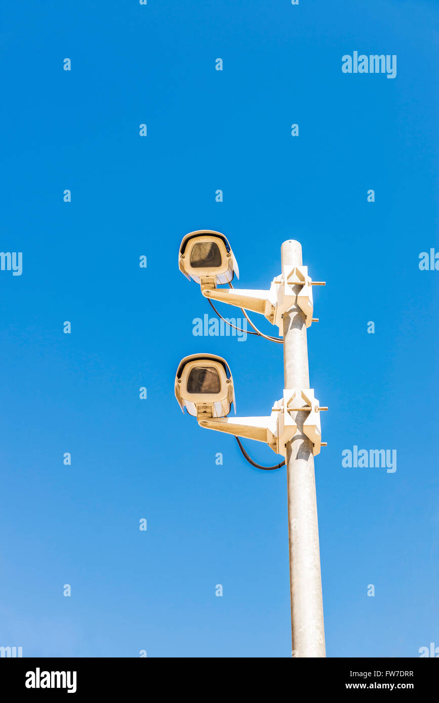 Two surveillance cameras against blue sky as background Stock Photo