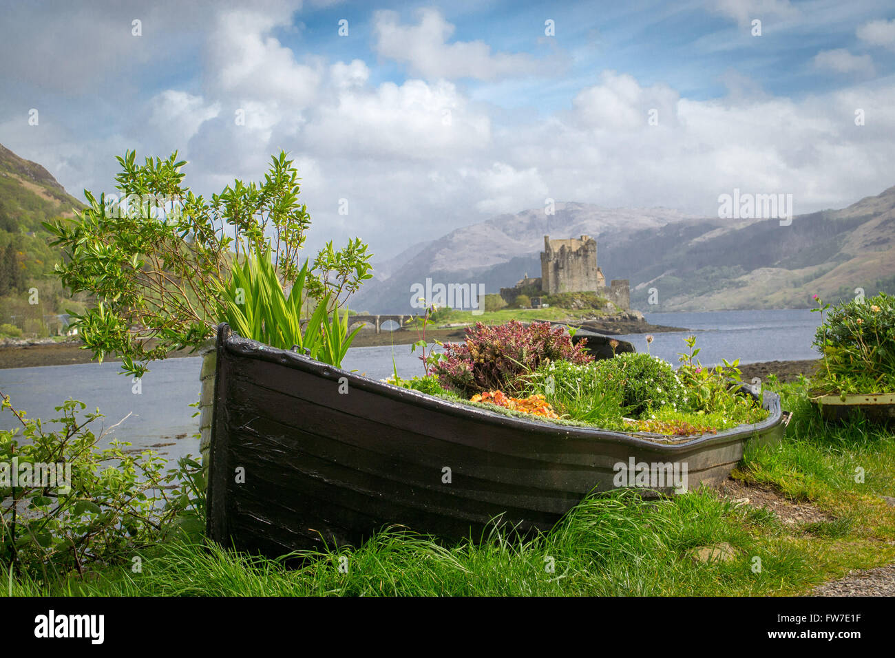 A rowboat is used a planter for flowers with Scotland's Eilean Donan Castle in the background. Stock Photo