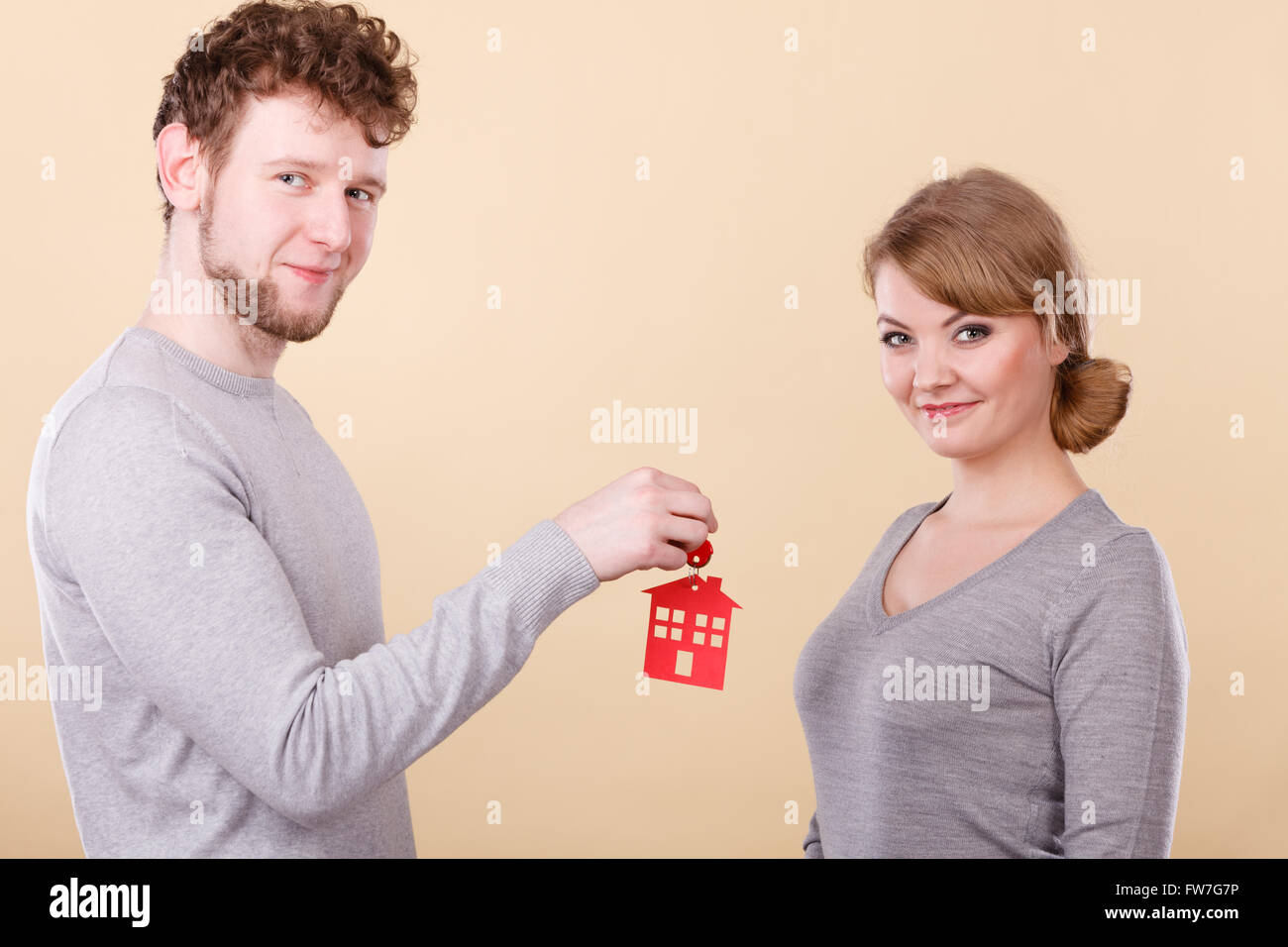 Young smiling couple woman and man holding new house key with red home ...