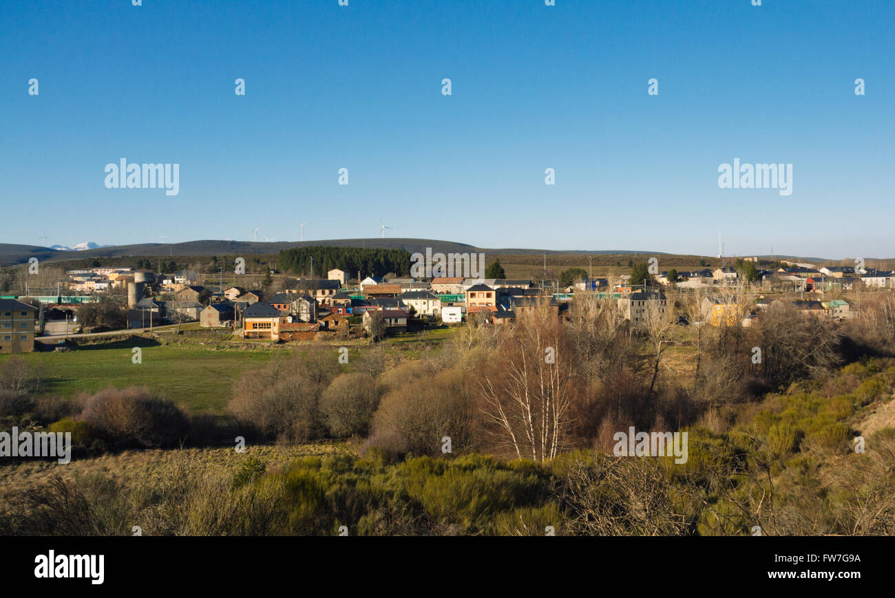 View of Brañuelas. Small village with blue sky, green foreground and wind farm on the hills. Stock Photo