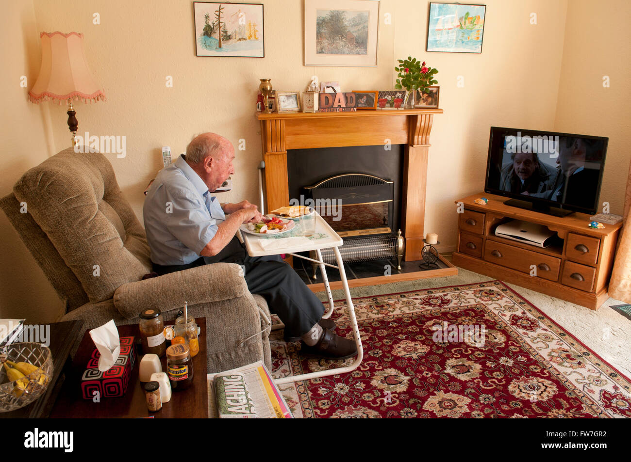 The Man Living In Our House Elderly man sitting inside eating, in his own home Stock Photo