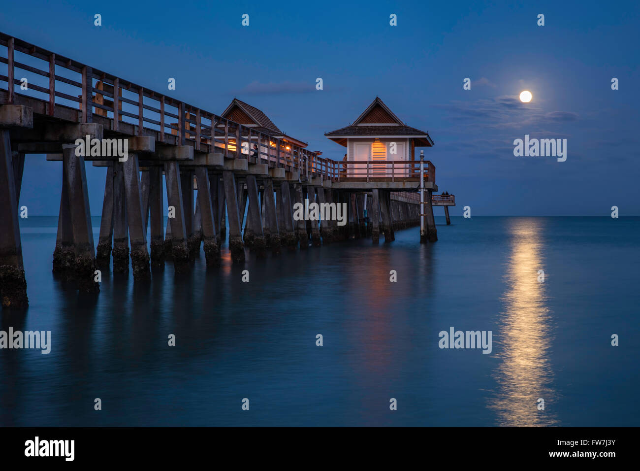 Full moon setting over the Naples Pier, Naples, Florida, USA Stock