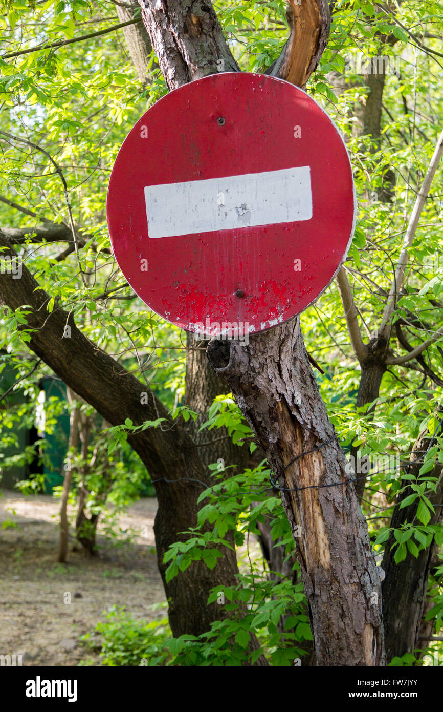 old "do not enter" sign with peeling paint on a tree Stock Photo