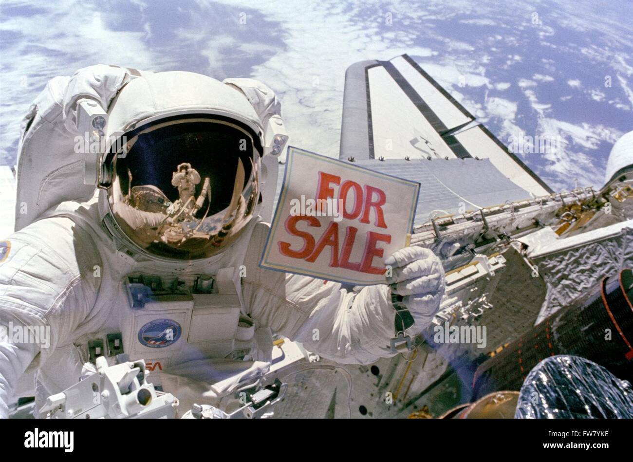 NASA astronaut Dale A. Gardner holds a "For Sale" sign referring to the
