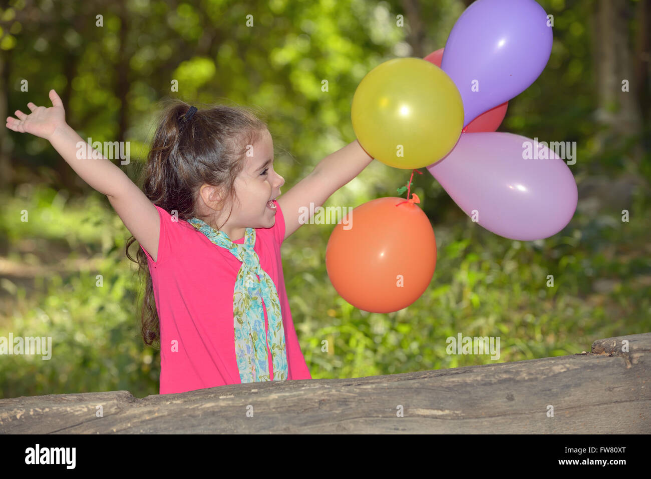 Little girl playing with balloons in forest Stock Photo