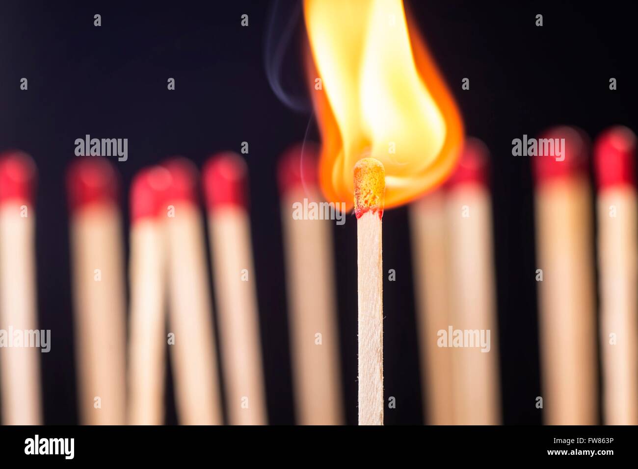 Burning matchstick in front of a new set of matches. Stock Photo