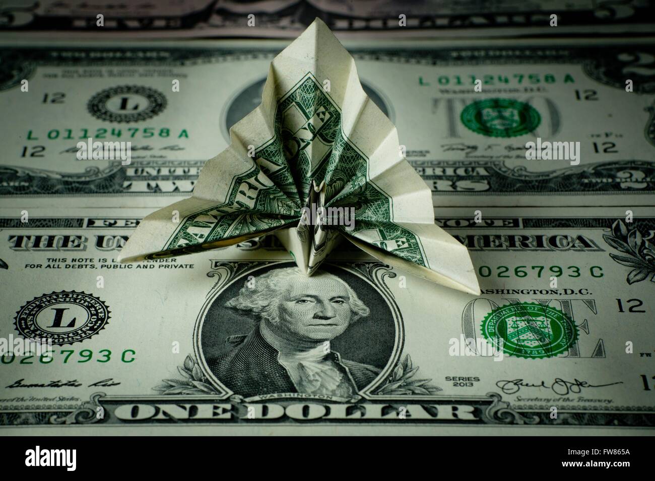 Origami peacock made of a dollar bill, sitting on dollar bills, in March 2016. Stock Photo