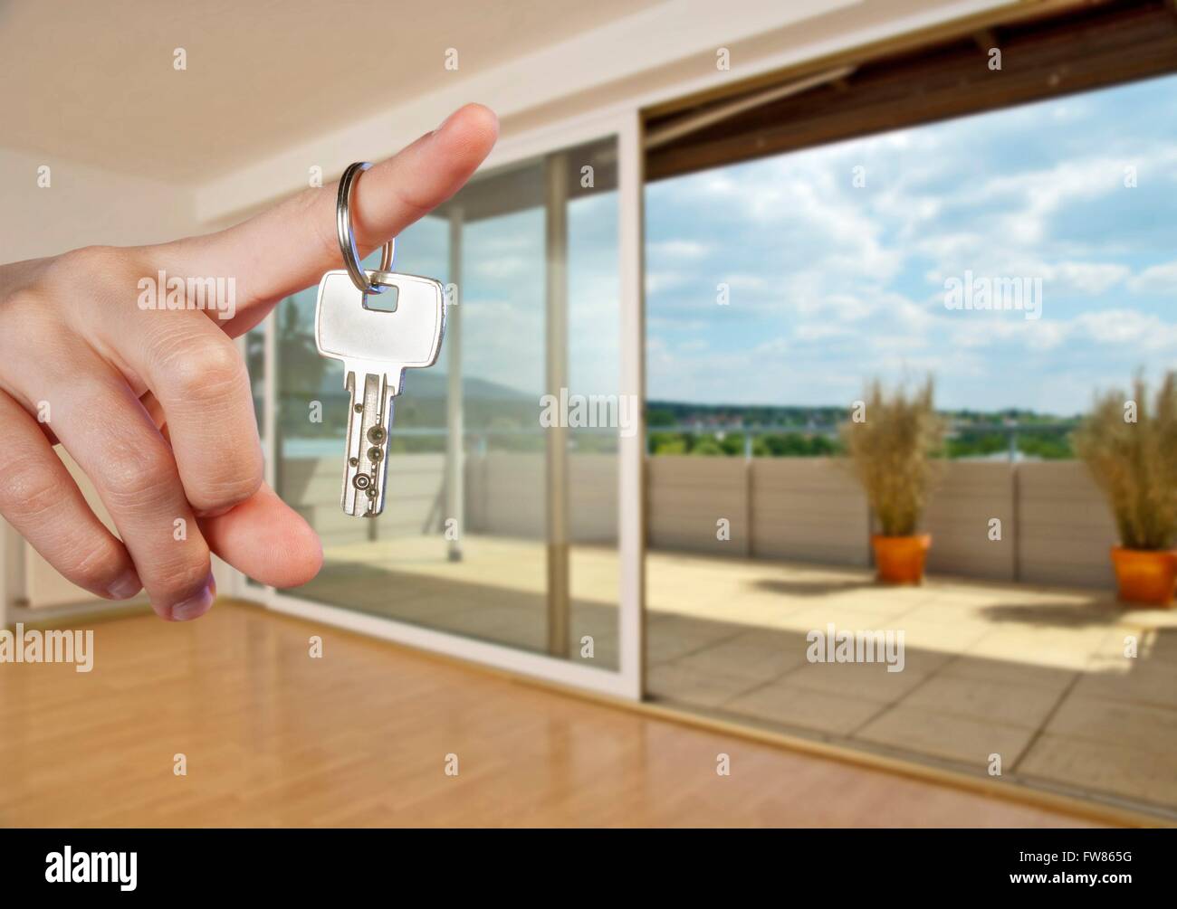 Apartment key on the finger of a hand in the interior of an empty apartment. Stock Photo