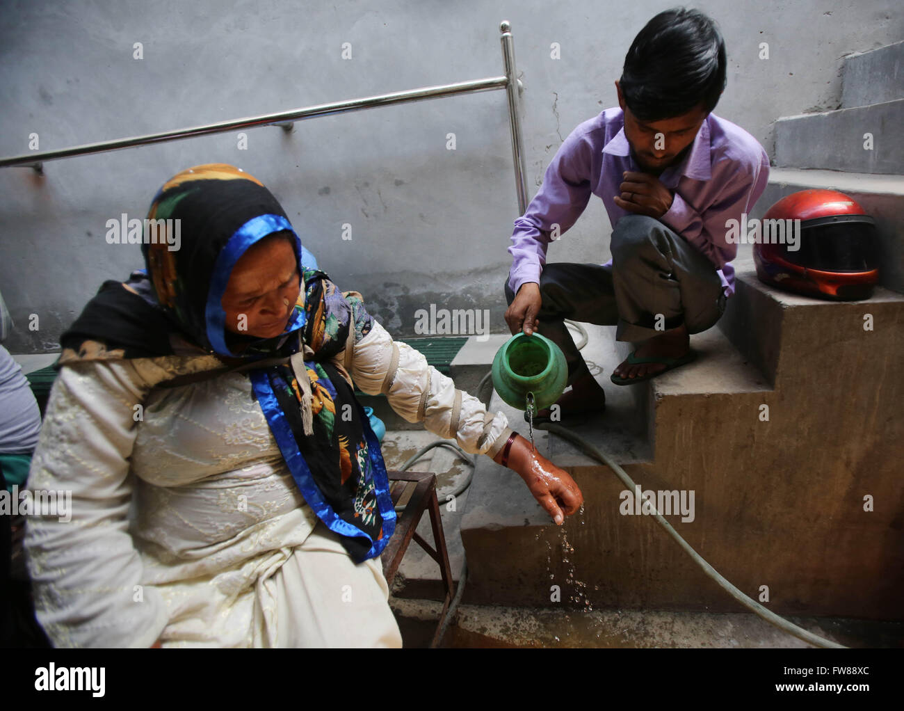 New Delhi, India. 1st April, 2016. A helper washes a hand of a patient after she was made cuts by Mohammad Iqbal, a practitioner locally know as Hakeem in Wazirabad Gaon village in North Delhi, India, April 1, 2016. An Open air clinic 'Rahat Open Surgery' boasts of curing its patients by using old practice of bloodletting. Credit:  Xinhua/Alamy Live News Stock Photo