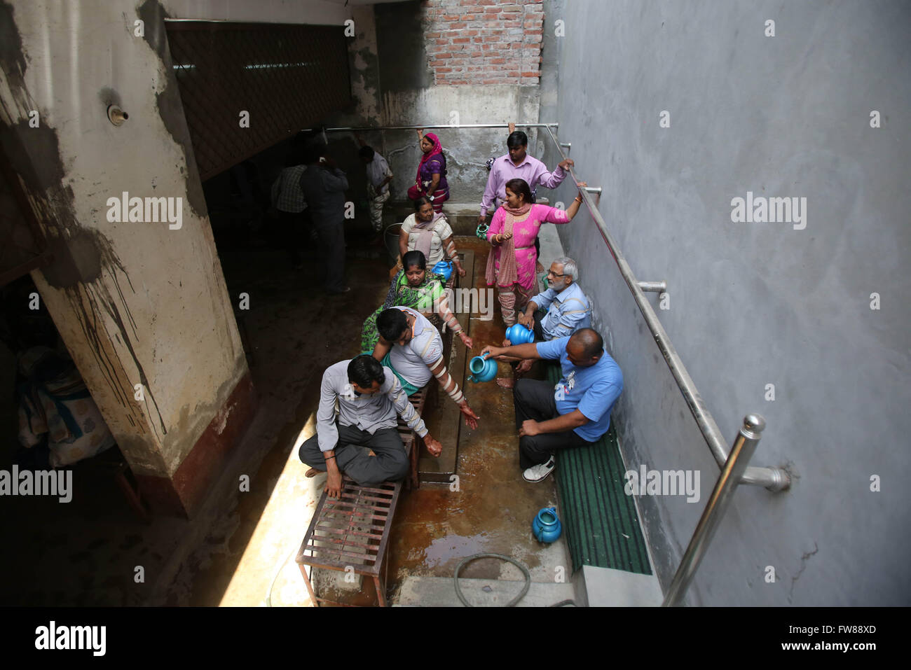 New Delhi, India. 1st April, 2016. A helper washes the hands of patients after they were made cuts by Mohammad Iqbal, a practitioner locally know as Hakeem, in Wazirabad Gaon village in North Delhi, India, April 1, 2016. An Open air clinic 'Rahat Open Surgery' boasts of curing its patients by using old practice of bloodletting. Credit:  Xinhua/Alamy Live News Stock Photo