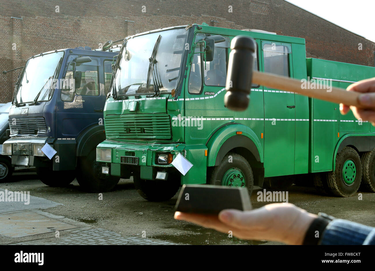 Duesseldorf, Germany. 1st Apr, 2016. ILLUSTRATION - Two disused police water cannons standing in a hall in Duesseldorf, Germany, 1 April 2016. In the front, a hand is holding a hammer used during auctions. The disused police vehicles and the vehicles of other public authorities are sold by auction at the Duesseldorf hall once per month. Photo: Roland Weihrauch/dpa/Alamy Live News Stock Photo