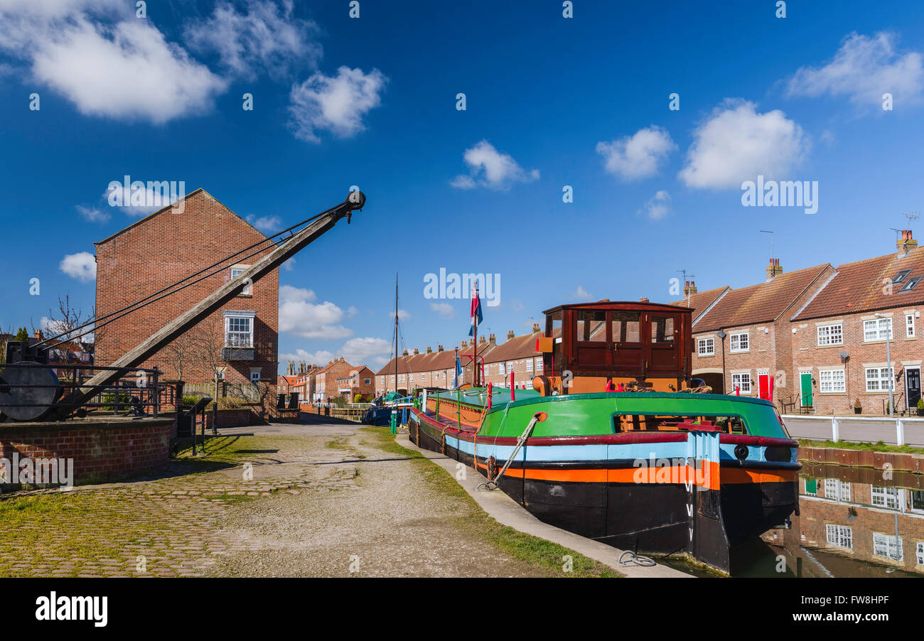 Restored barges, old winch, and town houses, along the beck (canal