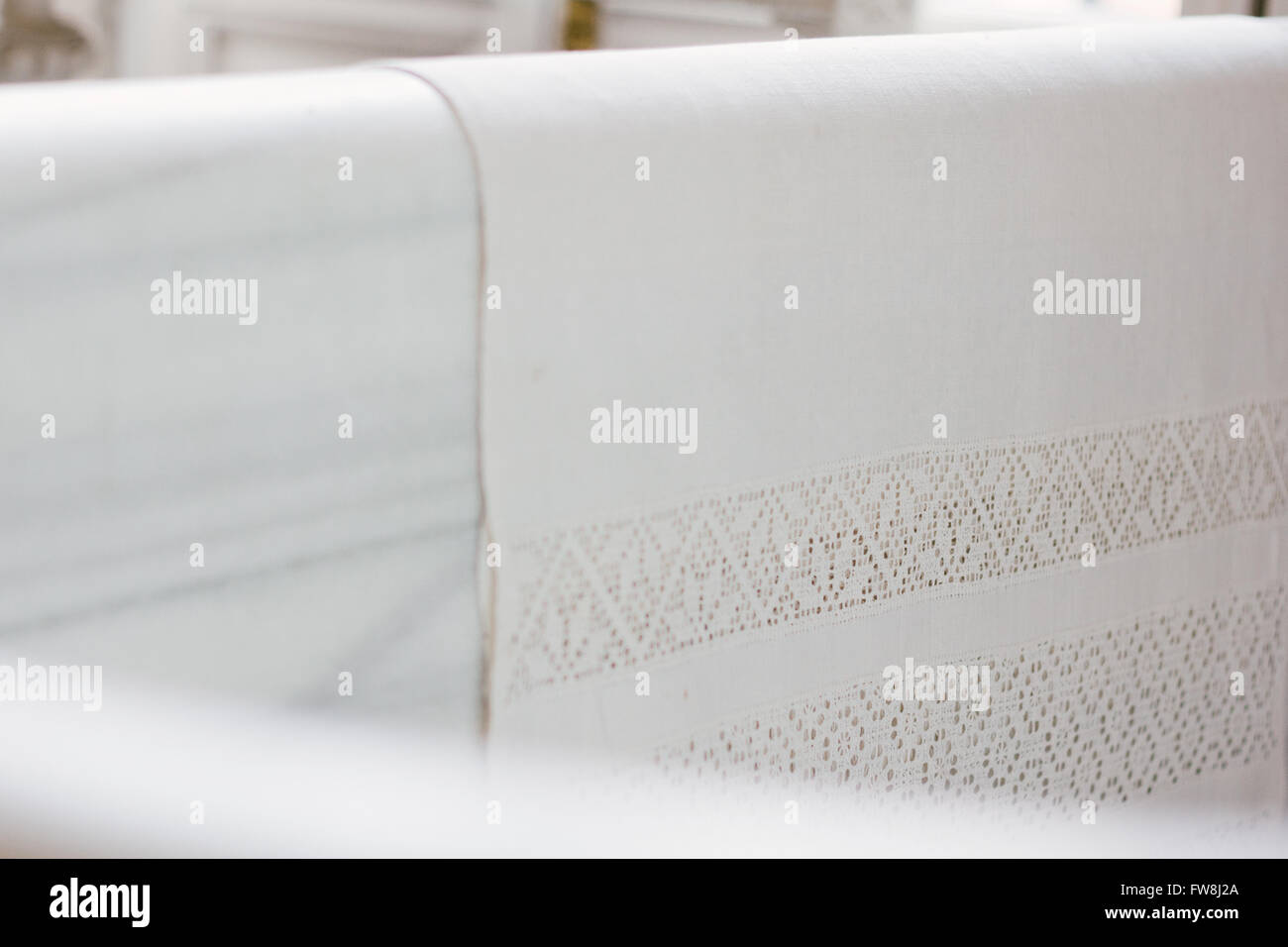 Detail of a sheet hanging on a white marble bathtub. Stock Photo