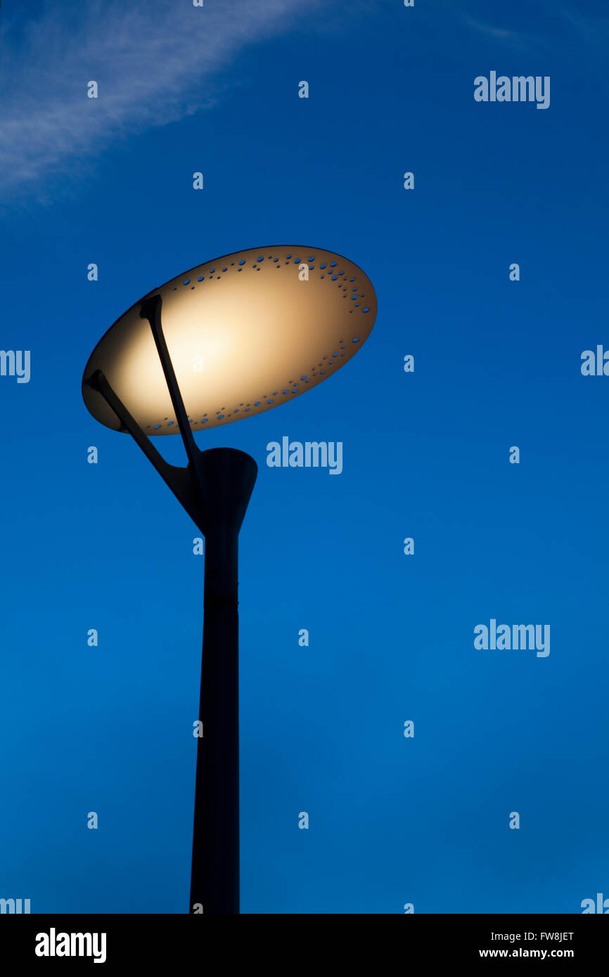 A modern street lamp refelcting the light downwards. AN energy saving plate has been placed over the top of the lamp creating more light on the ground and less light pollution in our cities. Stock Photo