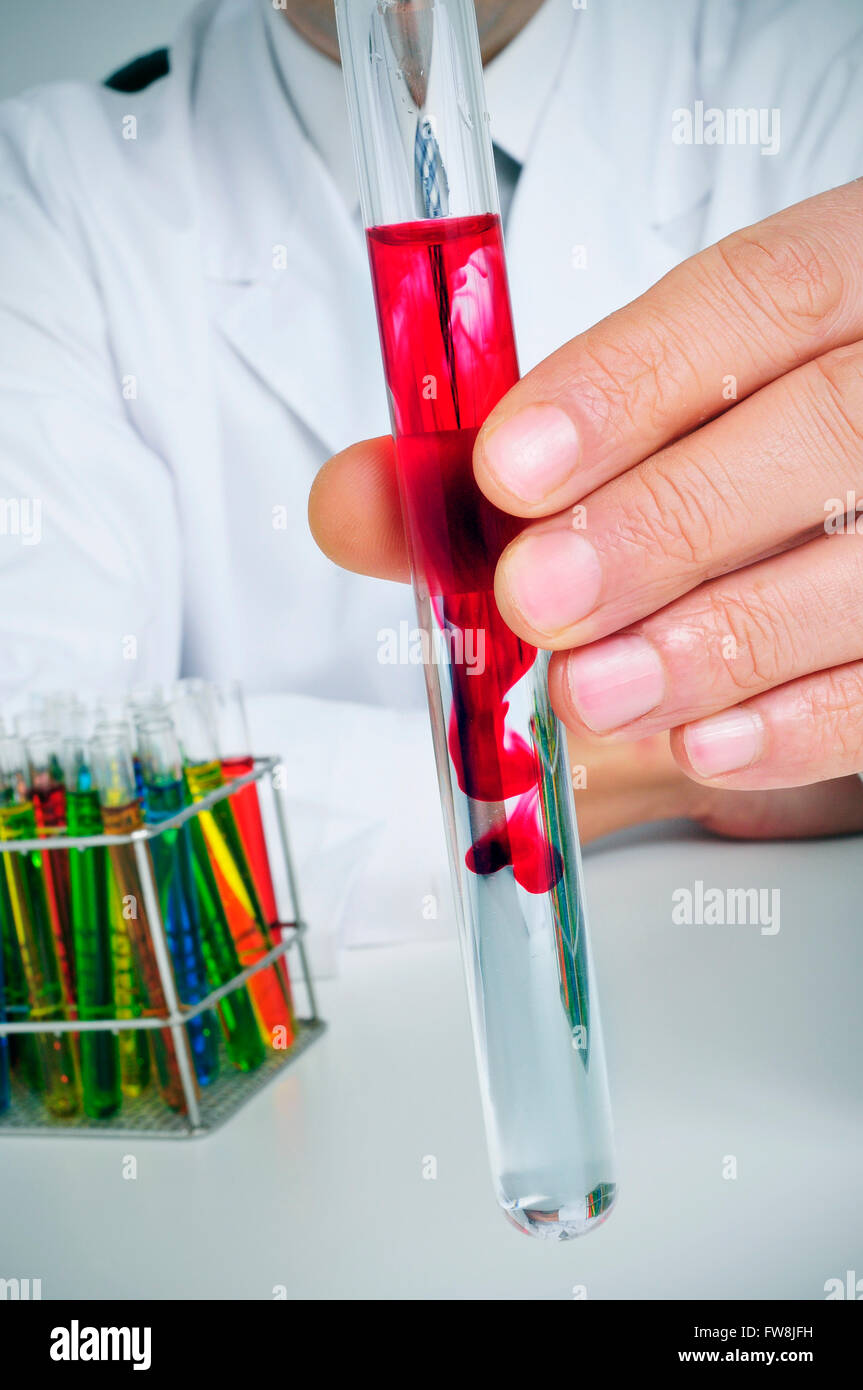 closeup of a young caucasian man in white coat with test tubes with liquids of different colors in a laboratory Stock Photo