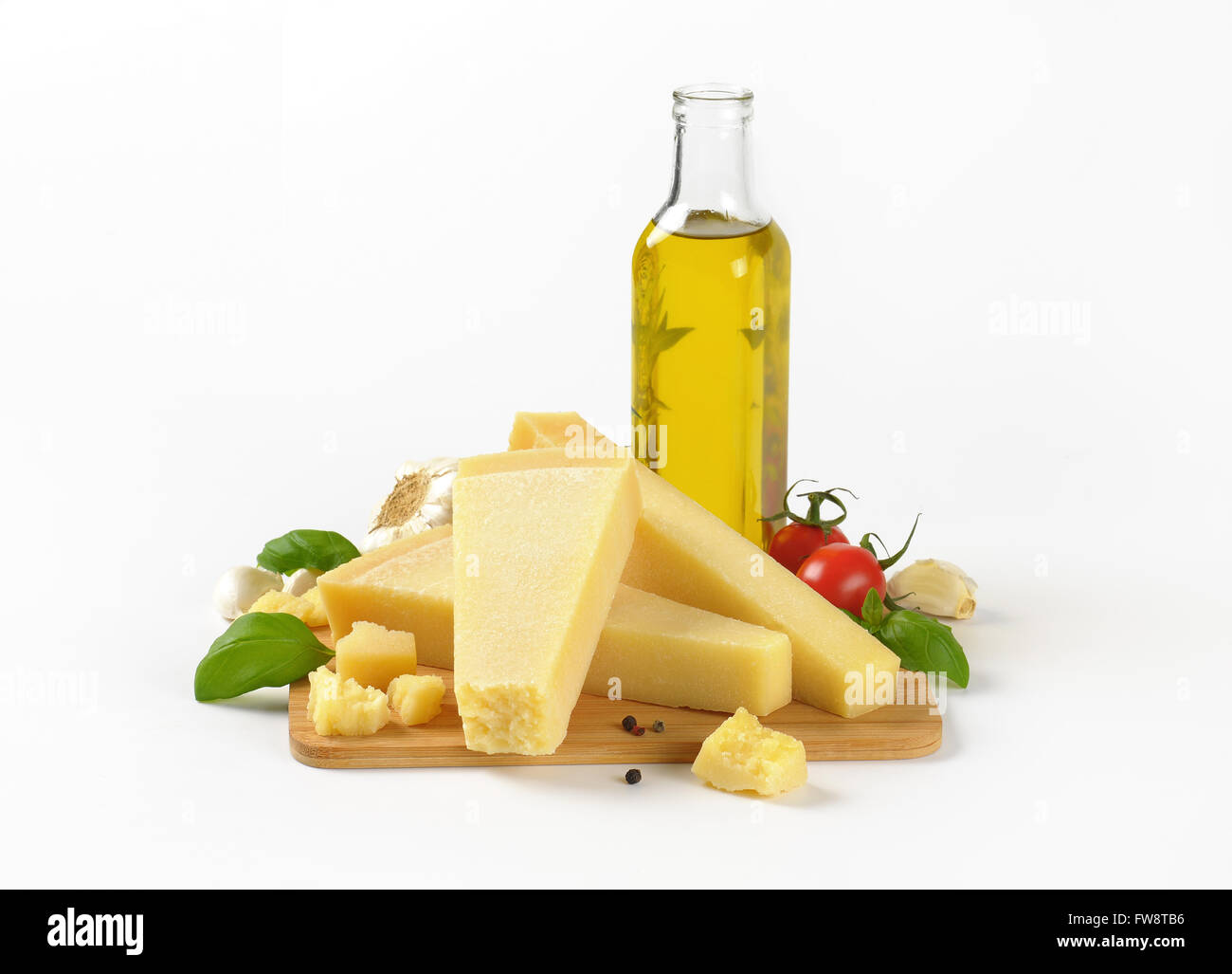pieces of fresh parmesan cheese, vegetable garnish and bottle of olive oil on white background