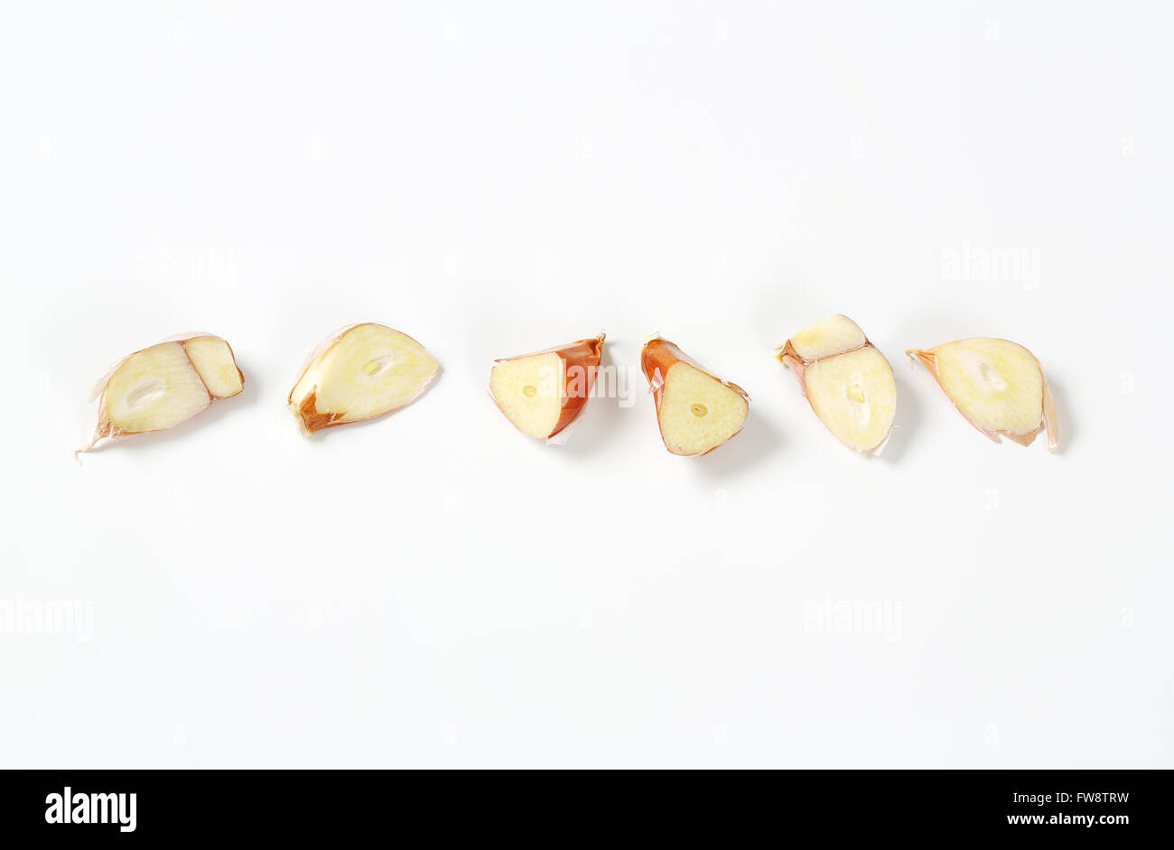 halved cloves of fresh garlic in a row on white background Stock Photo