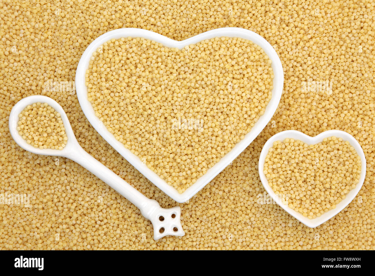 Pearl couscous food in heart shaped bowls and porcelain spoon forming an abstract background. Stock Photo