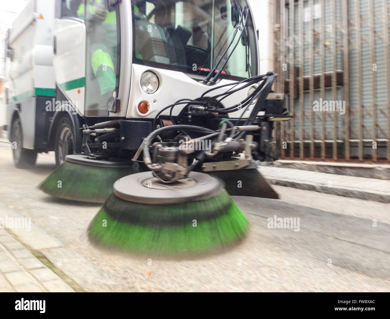 Street sweeper cleans old town street with brushes. Low motion shot
