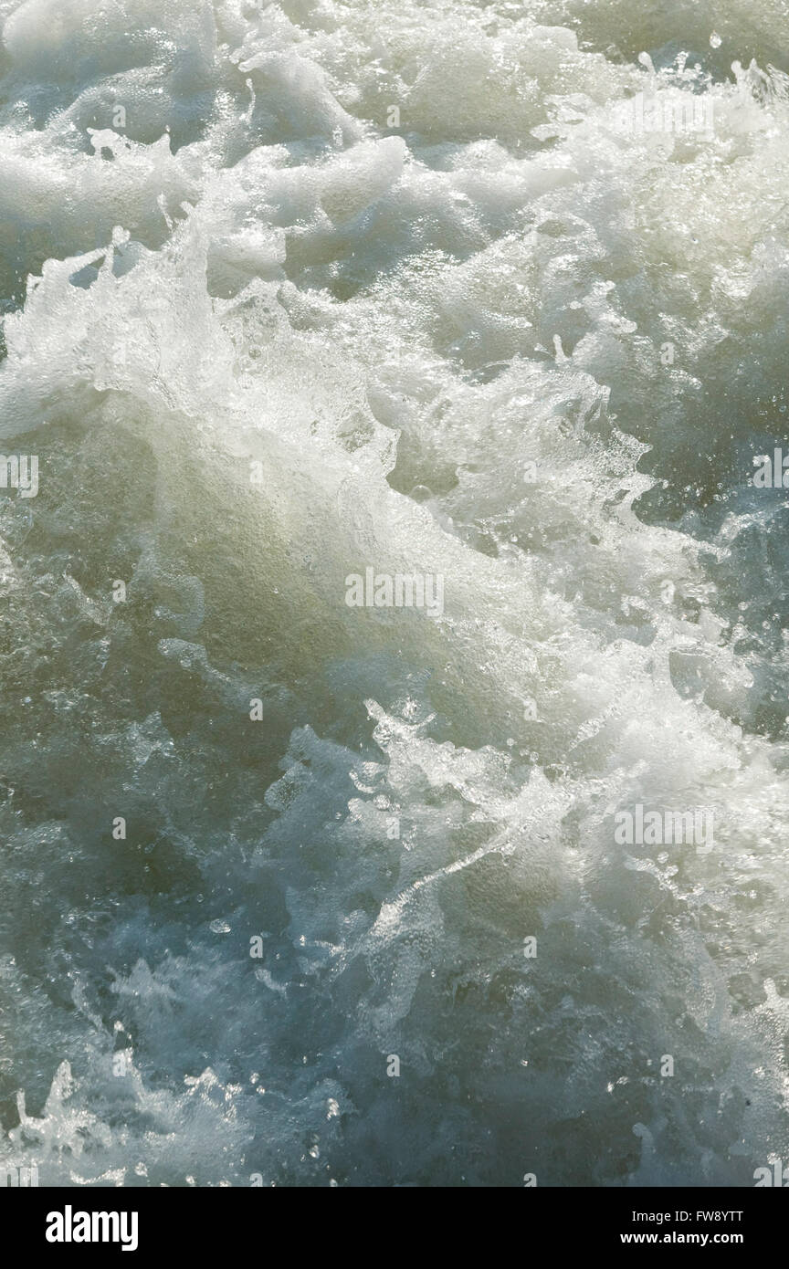 Water churning and bubbling with energy as it falls from a lock and weir system on a river in the UK. Stock Photo