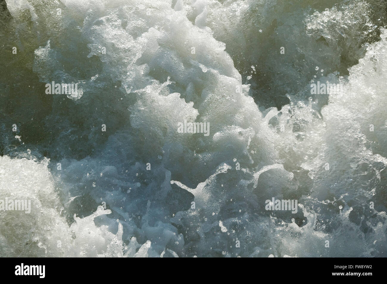 Water churning and bubbling with energy as it falls from a lock and weir system on a river in the UK. Stock Photo