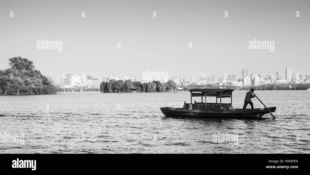 Hangzhou, China - December 5, 2014: Traditional Chinese wooden recreation boat with boatman on the West Lake. Famous park Stock Photo