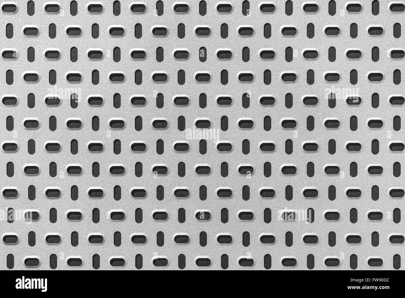 Light gray metal plate with punched pattern on a dark background Stock Photo