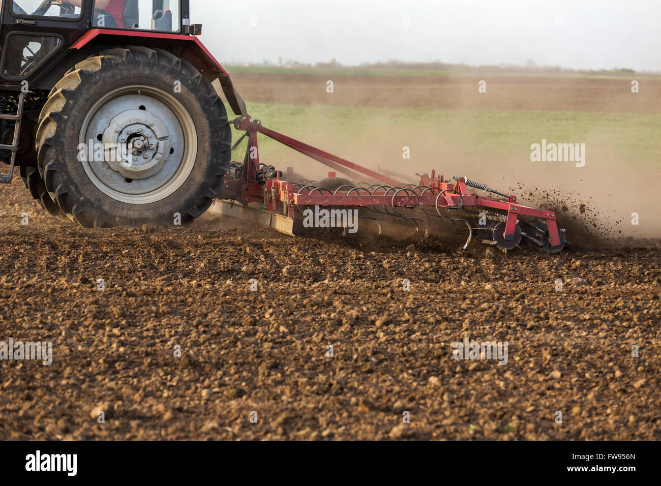 Tractor cultivating field at spring Stock Photo