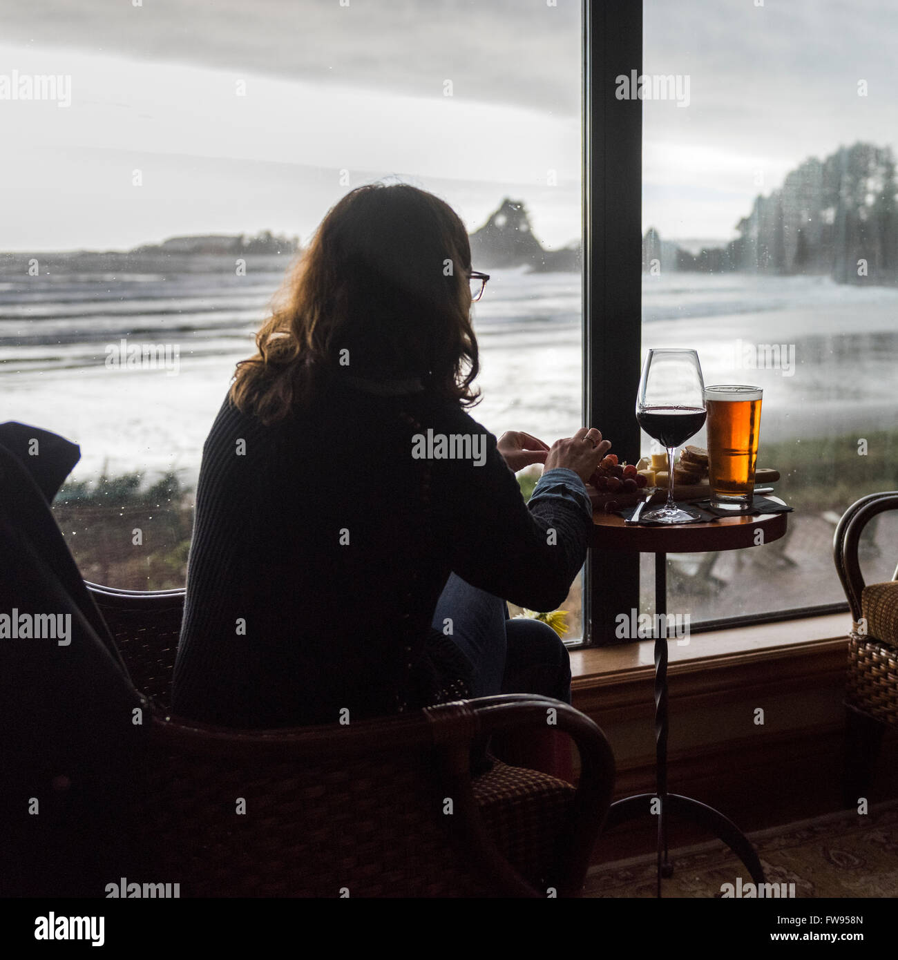 Woman sitting in a restaurant at seaside, Cox Bay, Pacific Rim National Park Reserve, British Columbia, Canada Stock Photo