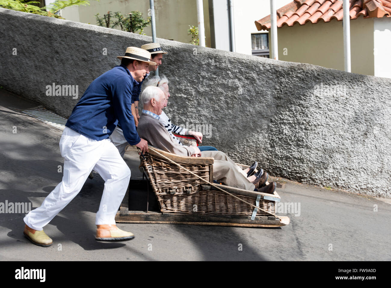 FUNCHAL,PORTUGAL-MARCH 19 Toboggan riders  dive with sledge with tourists on MArch 19, 2016 in Monte- Funchal, Portugal. This is Stock Photo