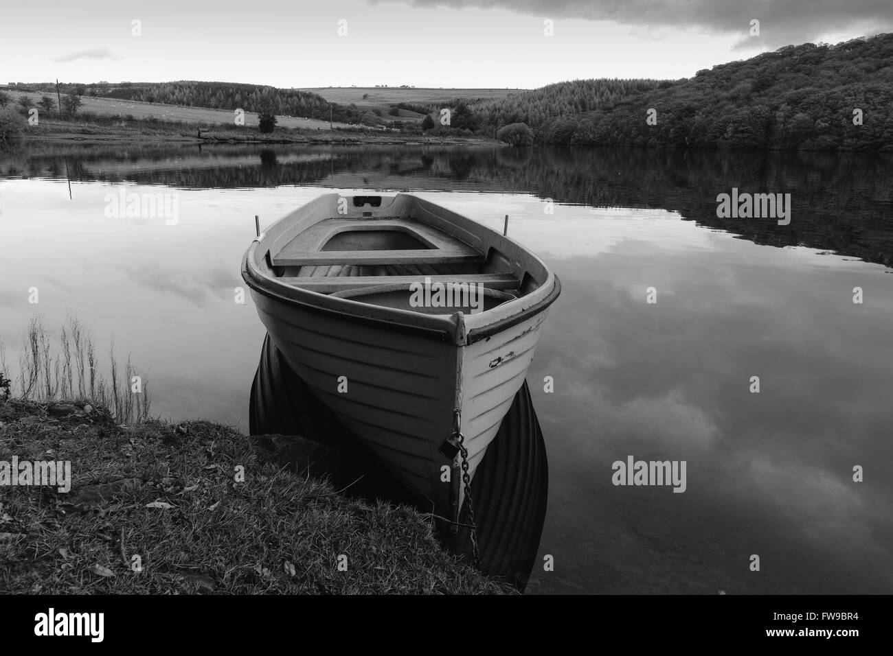 A rowing boat chained to the bank on a still morning on Tunstall reservoir near Wolsingham in Weardale, County Durham. Stock Photo