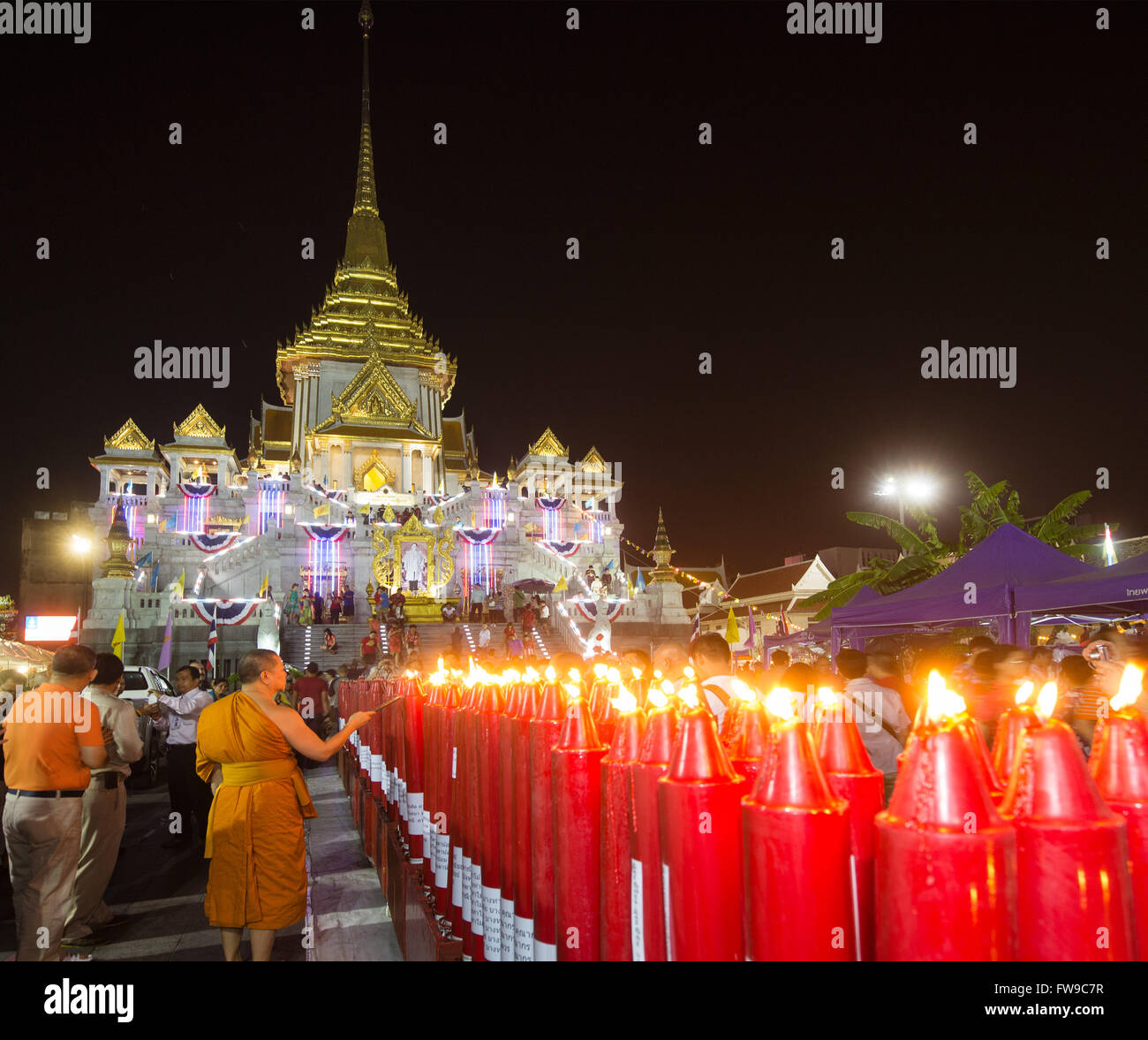 Illuminated Phra Maha Mondop of the Wat Traimit temple, monk lighting candles at the Chinese New Year, Chinatown, Bangkok Stock Photo