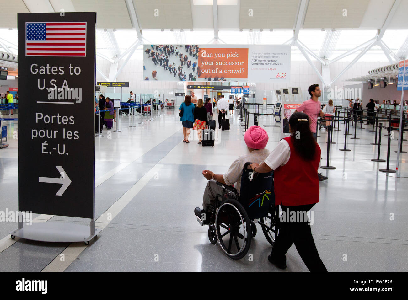 People walk toward the checked gate for flights to the U.S at terminal 1 at Pearson International airport in Toronto, Ont. Stock Photo