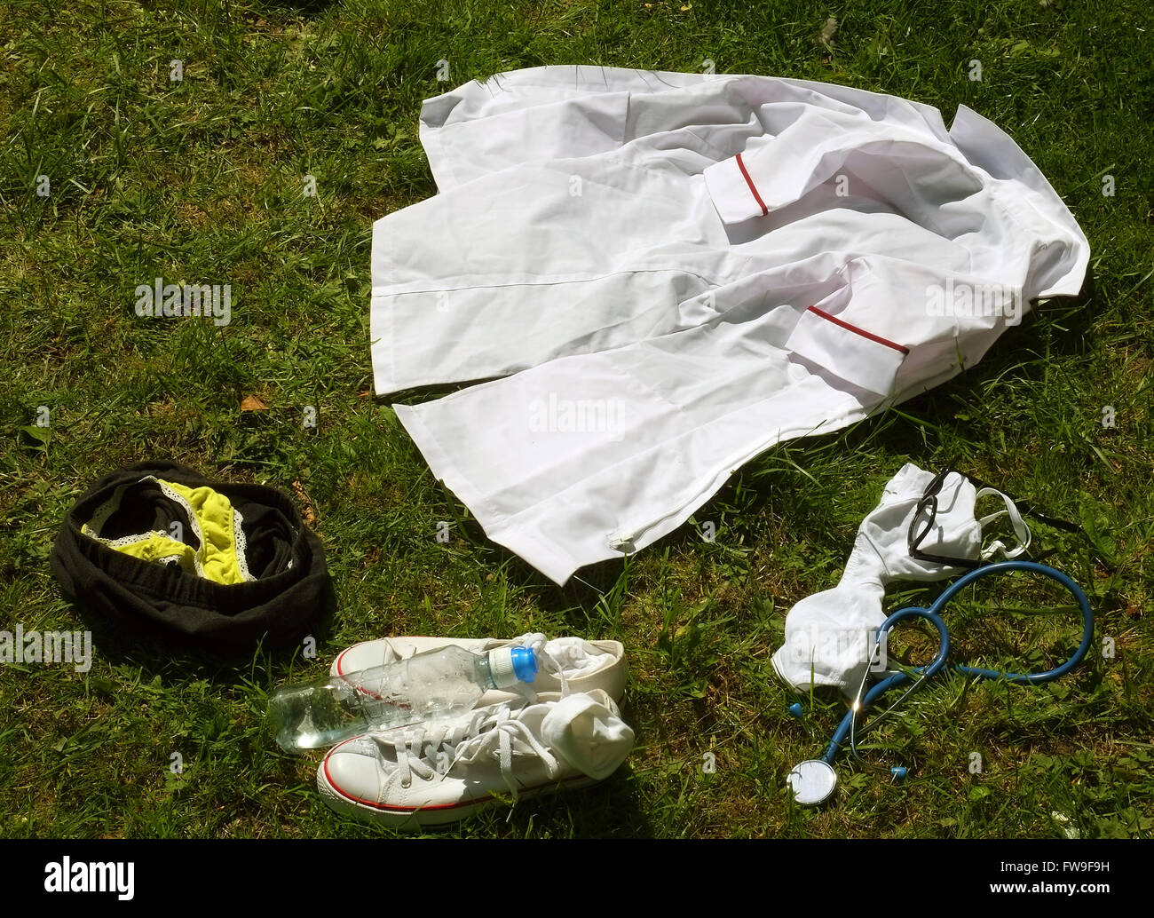 Pile of young female nurse or doctors clothing left on a grass meadow while they are sun bathing or skinny dipping 13th May 2015 Stock Photo