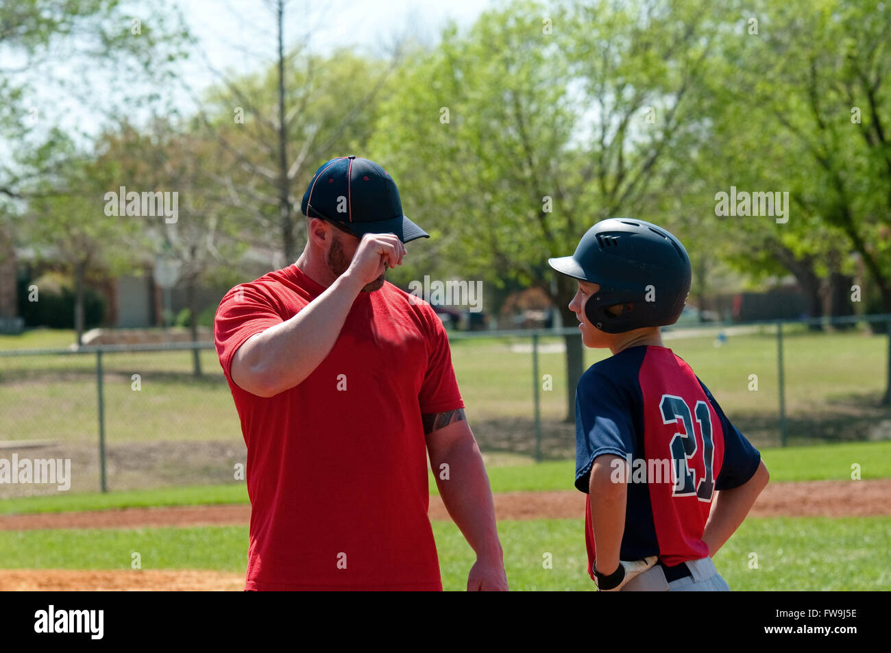 Baseball coach giving signals to teen player Stock Photo
