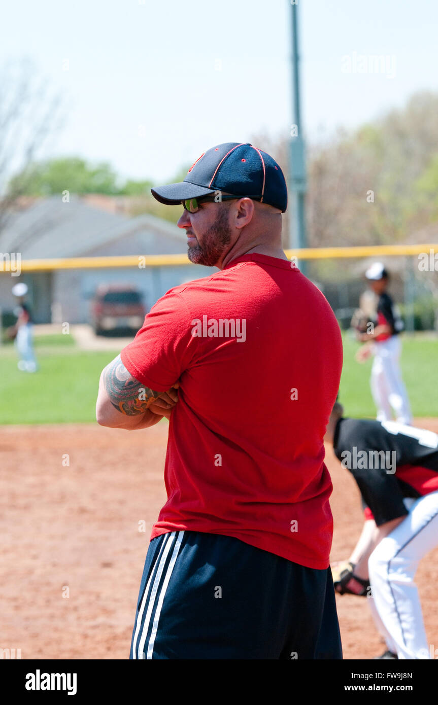 Baseball coach at first base line looking at batter. Stock Photo